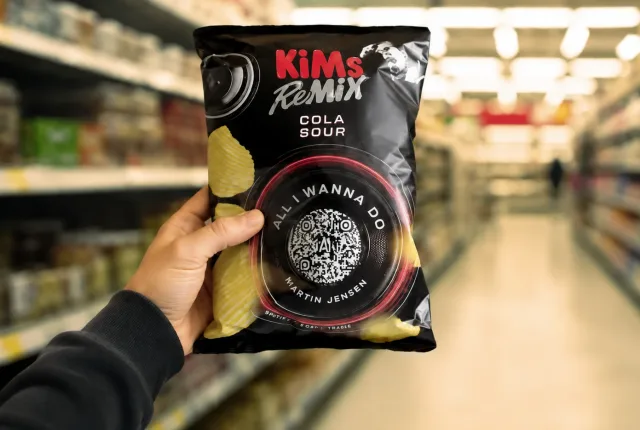 A pack of KiMs Remix with a QR code on it, held up in a supermarket aisle