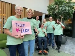 MS-forbundet team in green t-shirts holding a "Tusen takk" thank-you sign